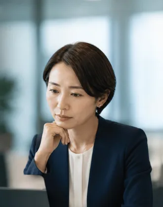 パソコンに向かって考え込む管理職の女性
